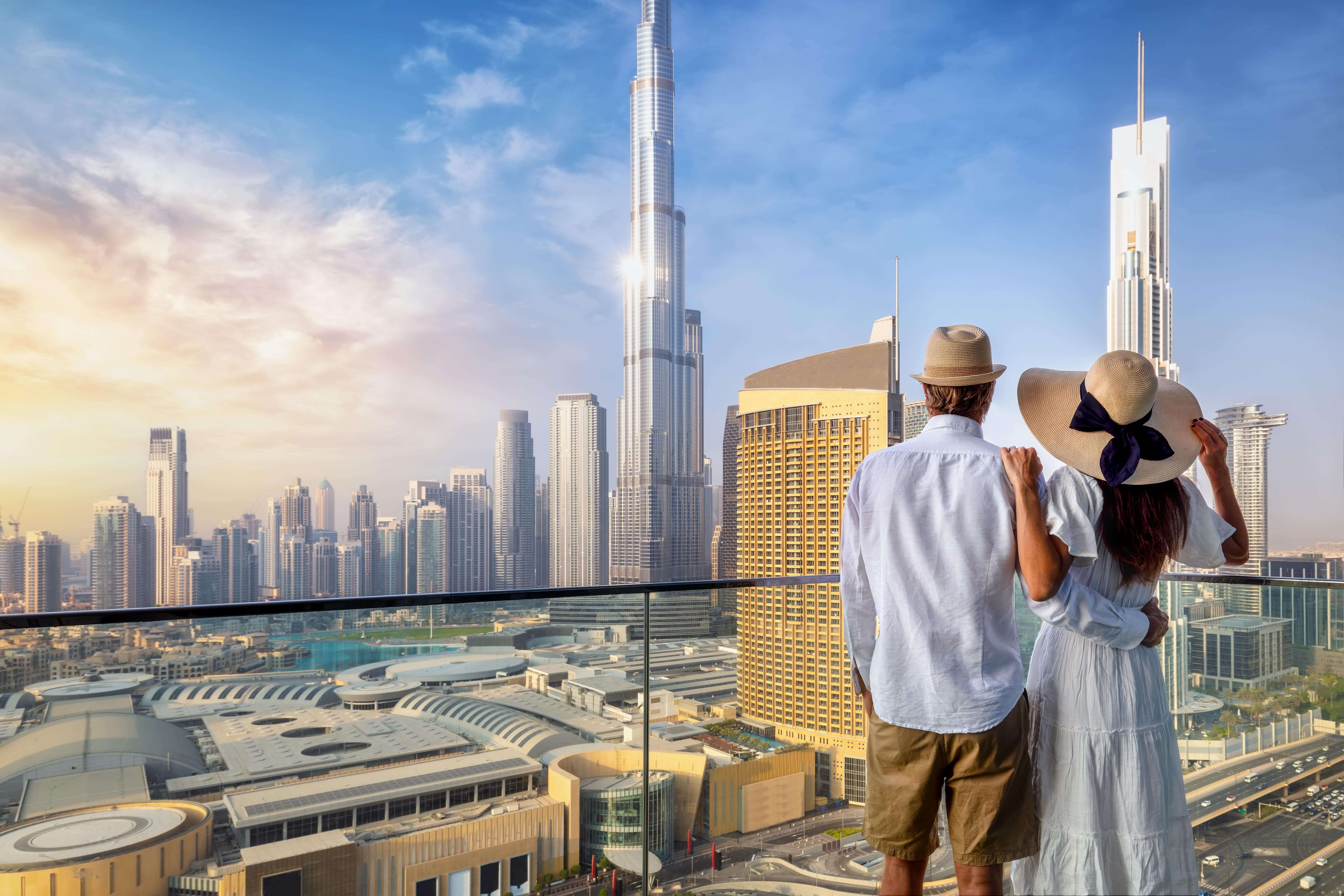 A couple on holidays enjoys the panoramic view over the city skyline of Dubai, UAE, during sunrise.